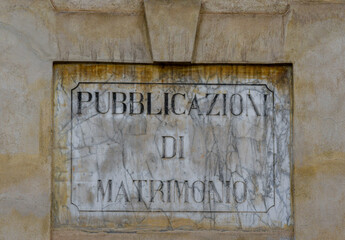 Close-up of a marble sign worn out by time that says: "Marriage Registrations", Italy