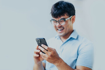 adult asian man using mobile, cell phone.young male person.posing smiling laughing look excited surprised thinking positive happy.empty,copy space for text advertising.grey background