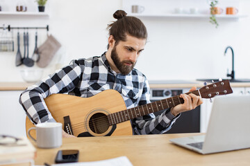 Happy male teaching online guitar lesson using modern technologies. Cheerful Caucasian person...
