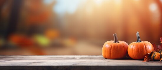 Two orange pumpkins and colorful leaves are displayed on a rustic wooden table, creating a natural foods still life scene - obrazy, fototapety, plakaty