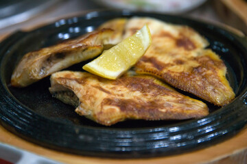 View of the roasted fishes with lemon on the dish