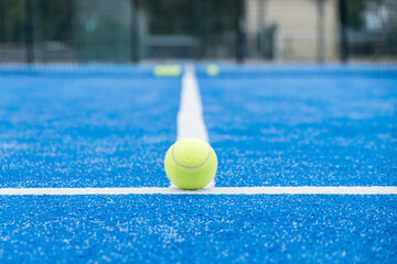 A paddle tennis ball is sitting on the blue court