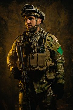 A focused Latin American soldier clad in tactical gear stands ready, exuding confidence and preparedness in a rugged backdrop