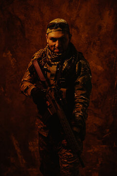 An intense image of a Latin American soldier shrouded in shadow, equipped with his rifle, standing against a dark, textured backdrop