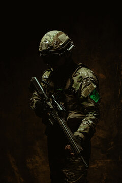 An enigmatic Latin American soldier enveloped in darkness stands with his rifle, showcasing a silhouette of readiness