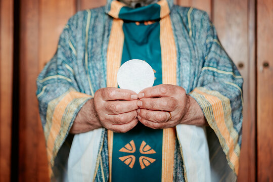 Close-up of anonymous priest's hands presenting the Eucharistic host, a sacred symbol in the Christian Holy Communion