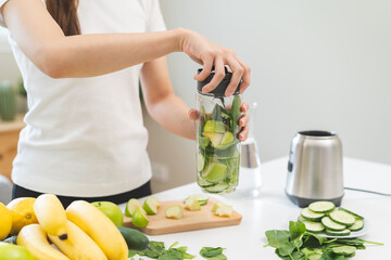 Vegetable smoothie detox, woman hand making healthy raw fresh green fruit juice with blender machine, preparing drink with spinach in kitchen at home, eating vegan diet. Healthy dieting, weight loss.