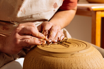 Crop artisan using ribbon tool on clay pot