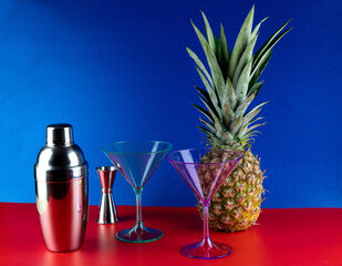 Cocktail Shaker with Cocktail Glasses and Pineapple on a Red Base and Blue Background - 761446851