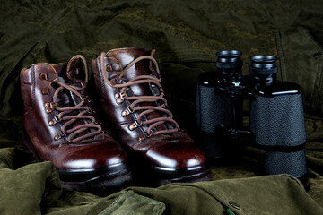 Old Hiking Boots and Binoculars on an Outdoor Field Coat - 761446887