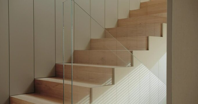 Wooden stairs with glass barrier in house with modern interior. Design of wood staircase in apartment.