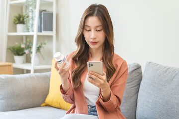 Health care asian young woman using smart phone for reading, searching prescription on bottle...