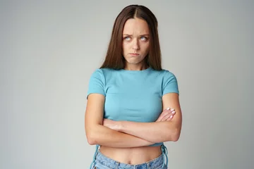 Foto op Canvas Portrait of sad displeased offended young woman in blue T-shirt on gray background © fotofabrika