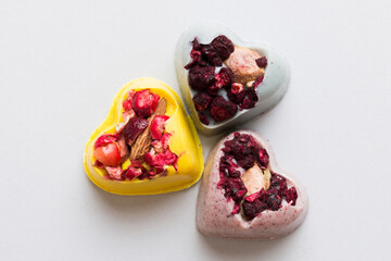 chocolate sweets in the form of a heart with fruits and nuts on a colored background. top view with space for text, holiday concept