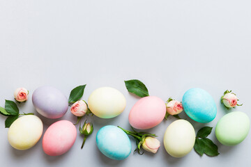 Happy Easter. Easter eggs on colored table with yellow roses. Natural dyed colorful eggs background top view with copy space