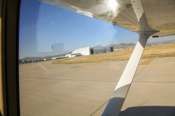 Under wing sight of landing light plane on runway at the airport.