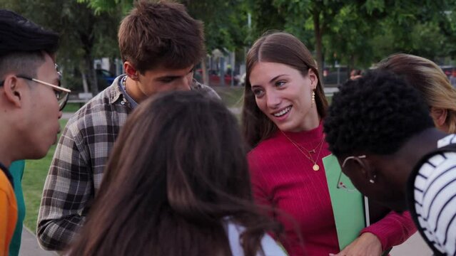 Dolly slow motion fotage of a big group of teenagers showing their cell phones. Young adult friends sharing on the social media app. Multiracial students talking and using their smartphones together