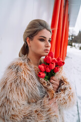 A girl in a bodysuit and a fur coat with flowers poses in different locations