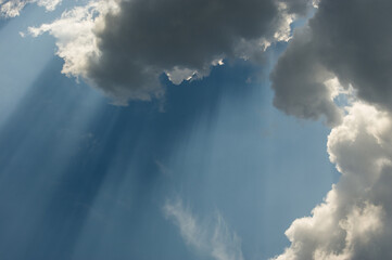 White clouds and rays of dark shadow against the background of the sky.