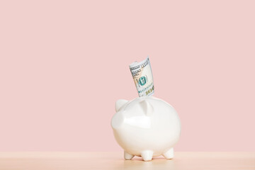 A folded one hundred dollar bill in a piggy bank. Saving money for the future