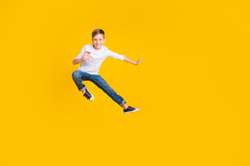 Fototapeta na wymiar Full length photo of funky positive kid dressed white shirt practicing karate jumping high empty space isolated yellow color background