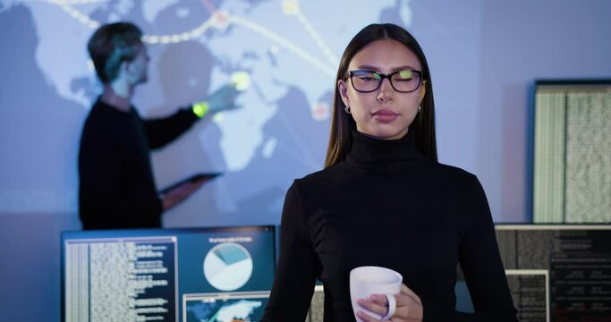 Confident female Cybersecurity Analyst or Manager in large Cyber Security Operations Center SOC handling Threats