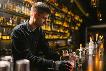 Bartender gives prepared glasses with drinks to visitors. Tired barkeeper finished doing last order...