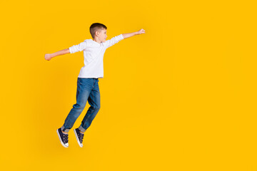 Fototapeta na wymiar Full length photo of good mood excited kid dressed white shirt jumping rising fist flying empty space isolated yellow color background