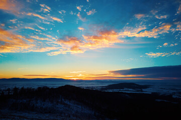 Sunset in mountains. Sun dips behind mountain peaks with golden light. Beautiful nature landscape
