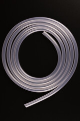 transparent plastic tube coil on black background.