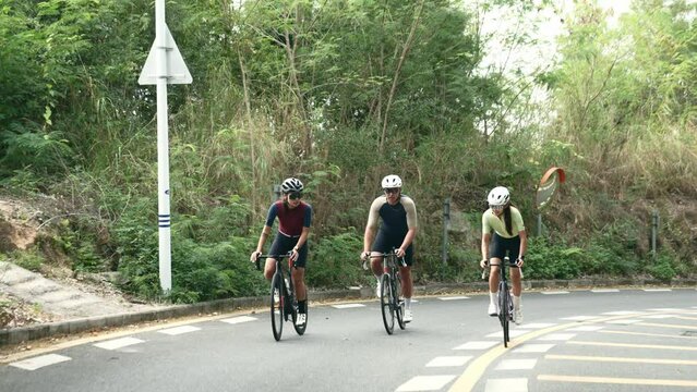 three young asian cyclists riding bike outdoors on rural road