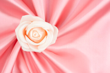 Pink satin fabric texture background with rose flower.