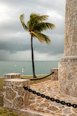 A palm tree near a lighthouse base blows in the wind on Boca Chita Island, Florida in Biscayne Bay

