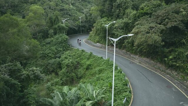 group of three young asian cyclists riding bike on rural road, drone shot