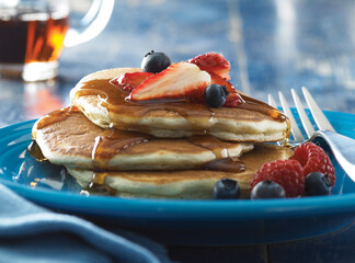 Stack of pancakes with syrup on blue plate