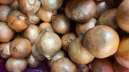 Close up pile of fresh onions placed together in local market as a background.
