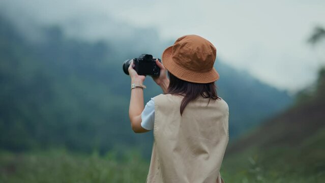 Happy young tourist female with camera taking photo of mountains and fog, Carefree woman in fields and stream, Rest on vacation holiday weekend