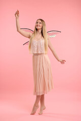 Beautiful girl in fairy costume with wings on pink background