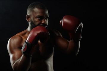 Dramatic low light shot of African American boxer in fight stance on black background