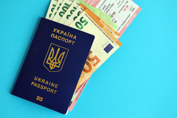 Ukrainian biometrical passport and european Euro money bills with Airlines avia tickets on blue background close up