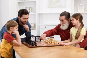Family playing chess together at table in room