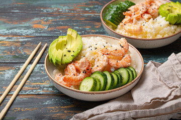 White ceramic bowl with rice, shrimps, avocado, vegetables and sesame seeds and chopsticks on colourful rustic wooden background front view. Healthy asian style poke bowl. - 761504668