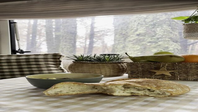 Interior of camper van motorhome with food on the table and forest view outside the window. Concept of vanlife and travel people vacation lifestyle
