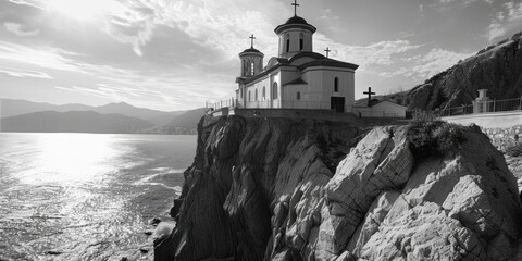 A striking black and white image of a church perched on a cliff. Ideal for religious or...