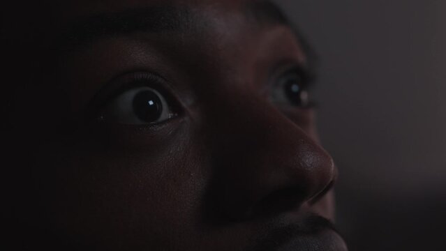 Young black male looks up at a screen in shock close up on his eyes