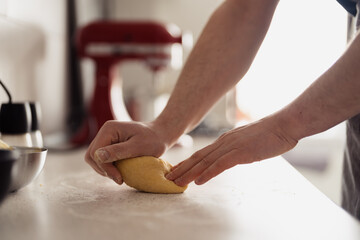Close-up of hands kneading dough on a kitchen counter with baking tools.