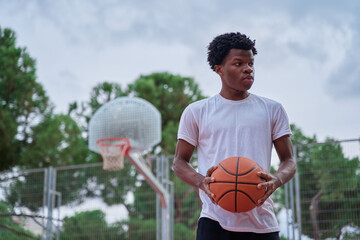 portrait of a young black man on a basketball court with a ball