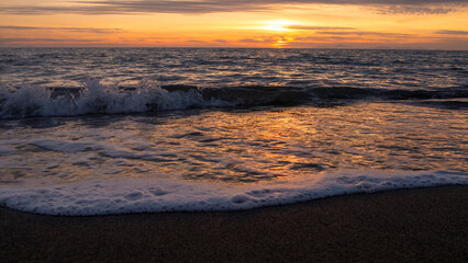 Fototapeta na wymiar tramonto al mare tra le onde