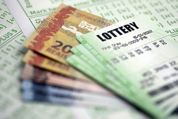 Green lottery tickets and brazilian reals money bills on blank with numbers for playing lottery close up