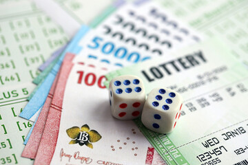 Green lottery tickets and indonesian money bills on blank with numbers for playing lottery close up